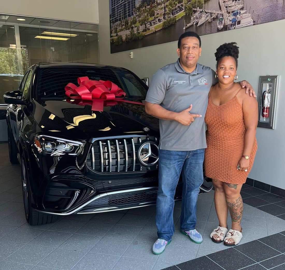 Martindale and a customer beside a black Mercedes-Benz SUV with a red bow