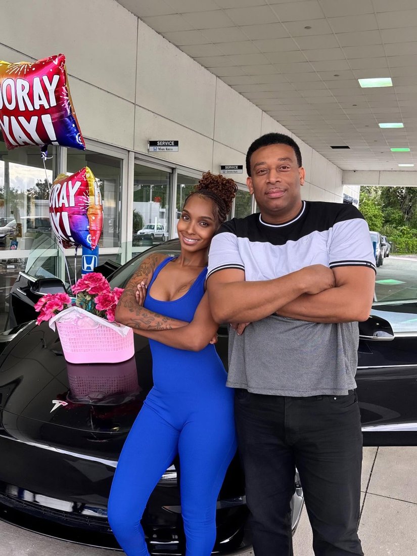 Martindale and a customer beside a Tesla with celebration balloons
